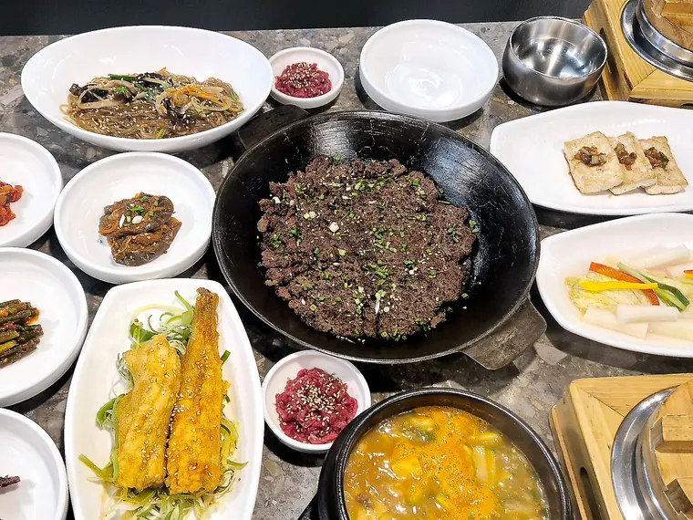 한우바싹불고기 한상. 무쇠판에 담긴 바싹불고기를 중심으로 장어튀김과 여러 밑반찬이 둘러져 있다.