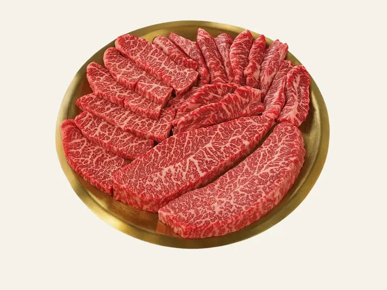 한우모듬구이. 살치살과 부채살, 갈비살이 놋쇠 접시에 나란히 담겨 있다.