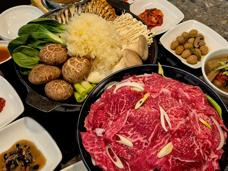 한우샤브불고기 한상. 얇게 썬 한우와 버섯 모둠, 채소가 담기고 밑반찬이 함께 차려져 있다.