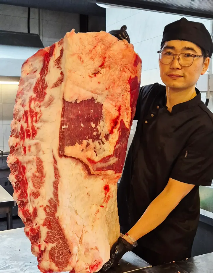 산들마을 요리사가 경매장에서 받아온 한우 원육을 손질 전에 들어 보이고 있다.