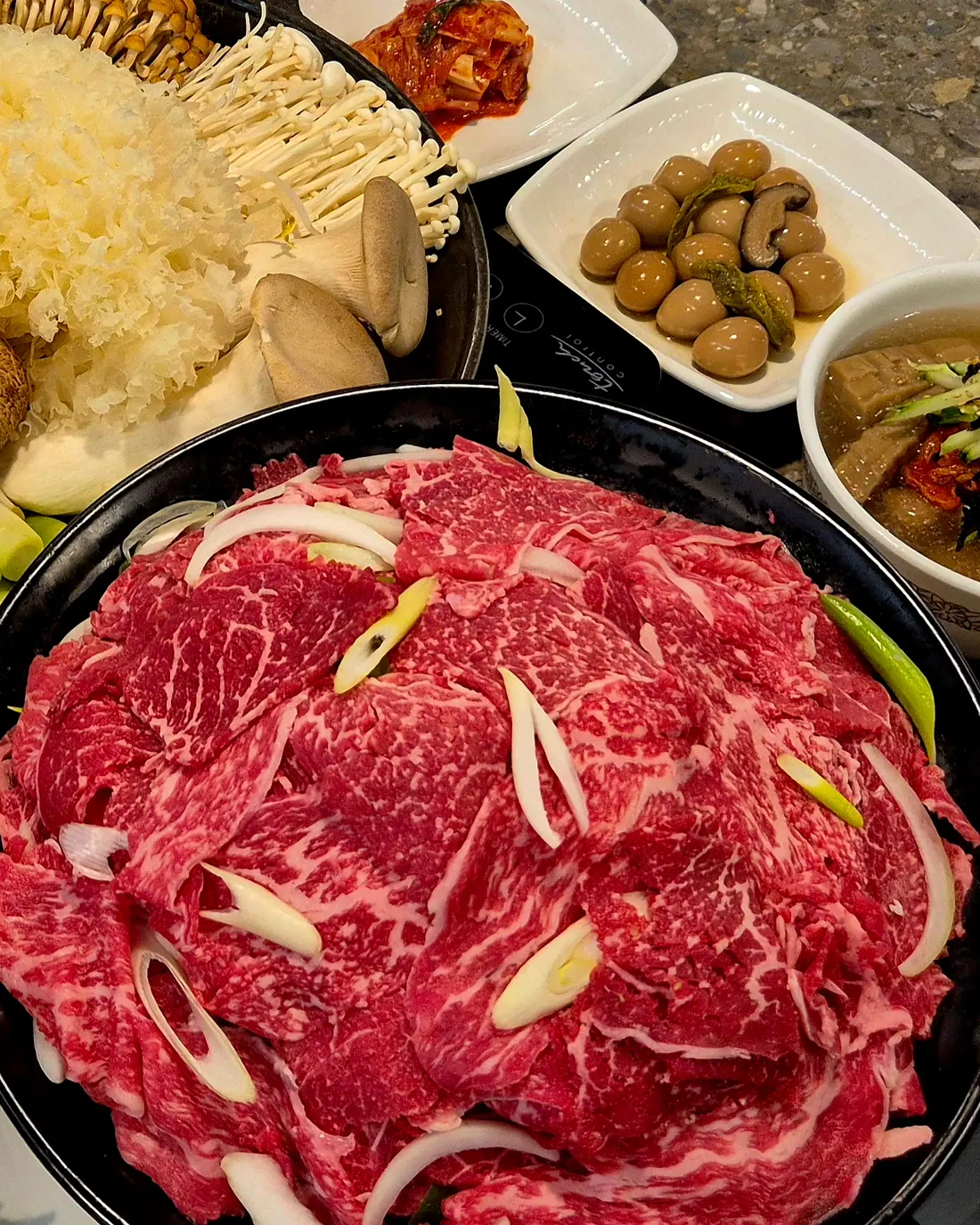 한우샤브불고기 한상. 마블링이 고른 1++ 한우와 버섯 모둠, 여러 가지 밑반찬이 함께 차려져 있다.